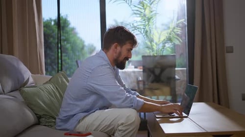 Man Working on Laptop Inside Sunny Home