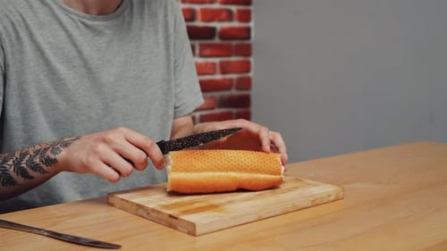 Man Preparing Lunch Man Sitting at Table at Home in the Kitchen and Preparing Sandwich Snack Cutting