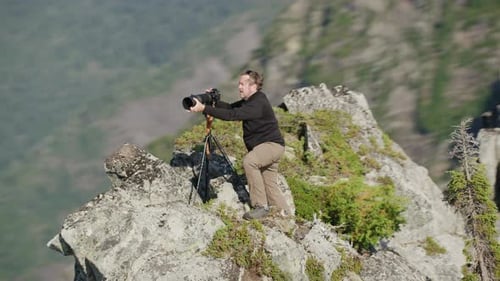 Photographer attaches hood to telephoto lens on camera on mountain ridge, Tim Durkan fast medium tra