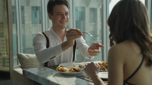 Sweet couple in love having romantic dinner at skyscraper rooftop restaurant bar