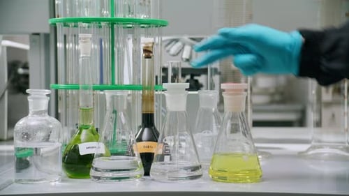 La main sélectionne le flacon jaune et change la verrerie du casier après