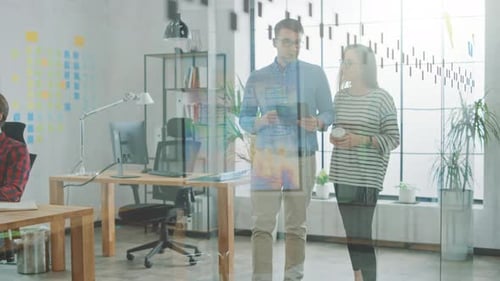 Young Woman and Man Colleagues Walking in the Office while Having a Friendly Discussion About New B