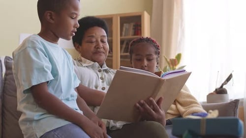 Children Reading Book with Adult Indoors During Daytime