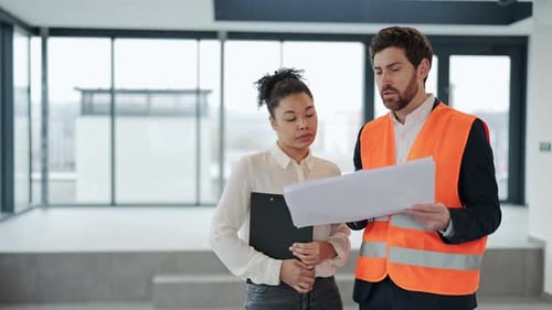 Businesswoman and Architect Discuss Blueprints in Modern Office