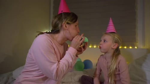 Mother Blows Up Balloon with Young Daughter