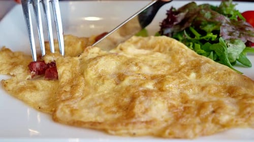 Cutting and Eating a Tasty Omelet with Salad