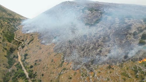 Wildfires burning on the side of the mountain releasing smoke and ash in the air