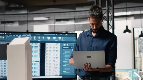 Male Developer Evaluating Architectural 3D Models and Plans
