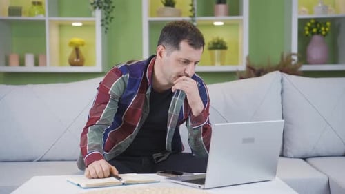 Unhappy and thoughtful man pauses and keeps thinking while working from home.