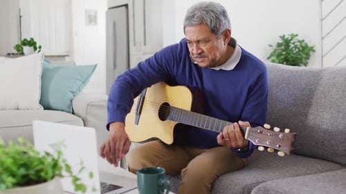 Senior Man Plays Guitar at Home