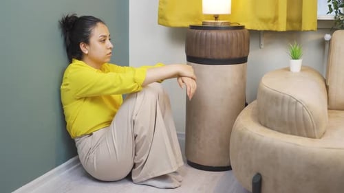 Sad Young Woman Sitting on Floor Indoors