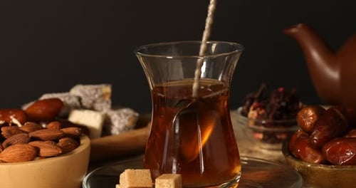 Adding and stirring sugar in glass with Turkish tea at table, closeup