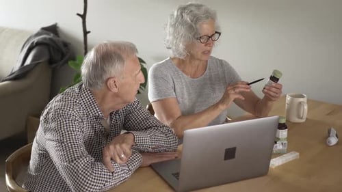 Senior Couple Discussing Medication Online At Home