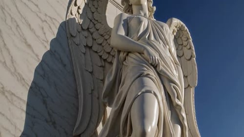 An Elegant Winged Angel Sculpture Gracefully Positioned Against a Bright Blue Sky Background