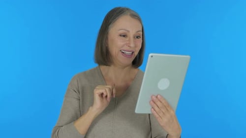 Smiling Woman Talking to Tablet on Blue Background