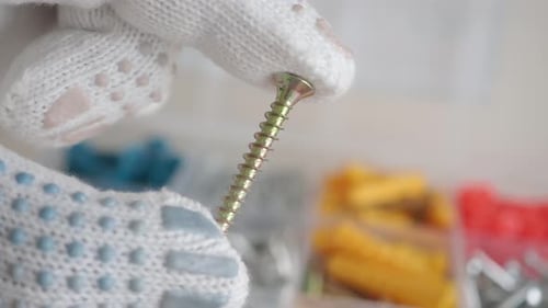 Gloved Hand Holds Metal Screw Close Up