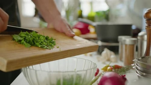 Person Adding Fresh Herbs to Glass Bowl