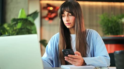 Professional Businesswoman Engaged in Digital Work with Laptop and Phone at Cafe