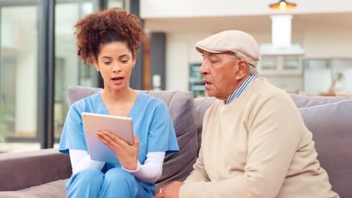 Caring Nurse Explains Tablet to Senior Man at Home