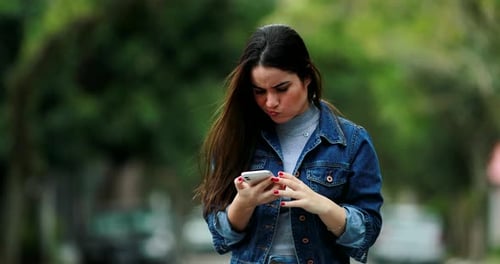 Woman receiving message on cellphone covering mouth with hand in unbelief