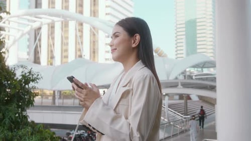 Portrait of young beautiful businesswoman using smartphone in modern city