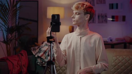 Sofisticado hombre pelirrojo vestido de mujer imparte cursos de maquillaje en línea en Neons Light Interior