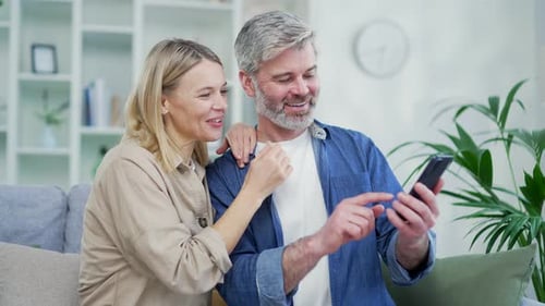 Couple Enjoying Smartphone on Sofa at Home