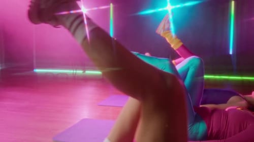 Cheerful Girls Enjoying Bicycle Exercise during Group Workout in Retro Gym