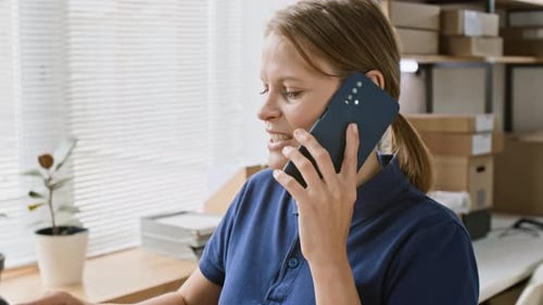 Woman Talks on Phone in Office with Boxes