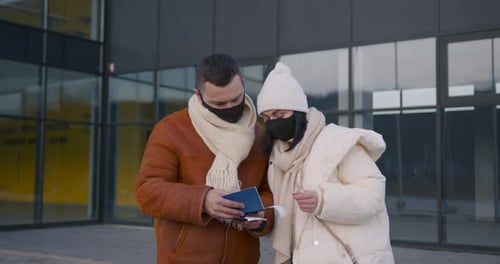 Happy Couple in Masks in Front of the Airport