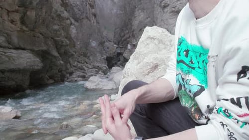 Der Mann sitzt am felsigen Gebirgsfluss. Stock-Filmmaterial. Der Mensch ruht sich aus und sitzt am Gebirgsfluss in Felsen.