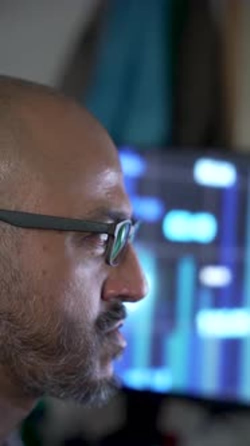 Südasiatischer Mann mit Brille analysiert Daten mit Börsenbildschirm. Vertikales Video