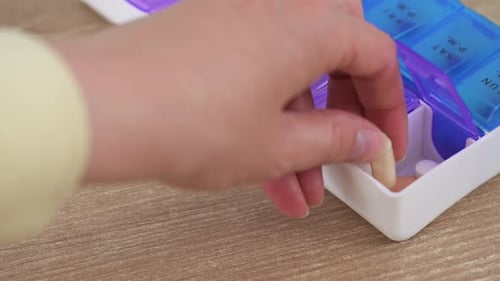 Woman take pill from weekly organizer.