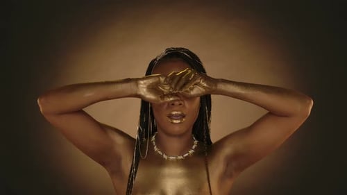 An African American Woman Demonstrates Her Hands Covered in Gold Paint Seminude Woman with Creative