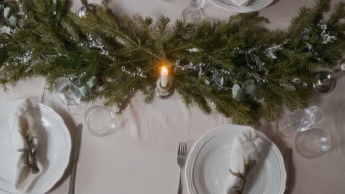Top Down of Christmas Dinner Table with Pine Branch Centerpiece and Candlelight