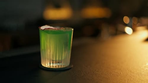 Nahaufnahme eines köstlichen grünen Cocktails mit Apfel, der auf der Bartheke aus Stahl und Holz auf Blurred steht