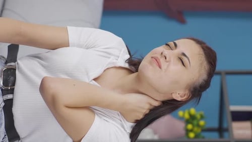 Woman Reclining Massaging Neck in Discomfort