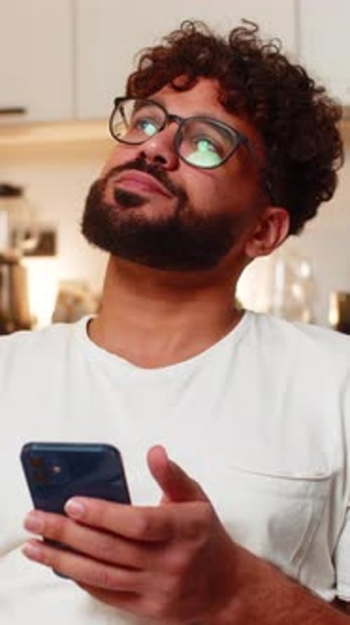 Man with curly hair looks at his phone