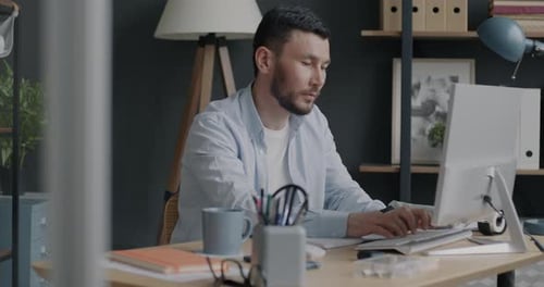 Serious Biracial Man Working with Personal Computer Typing with Keyboard in Office
