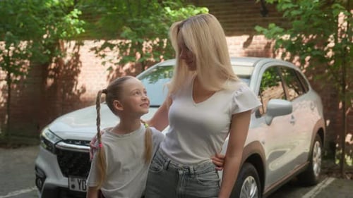 Woman and Girl Standing Together by Car