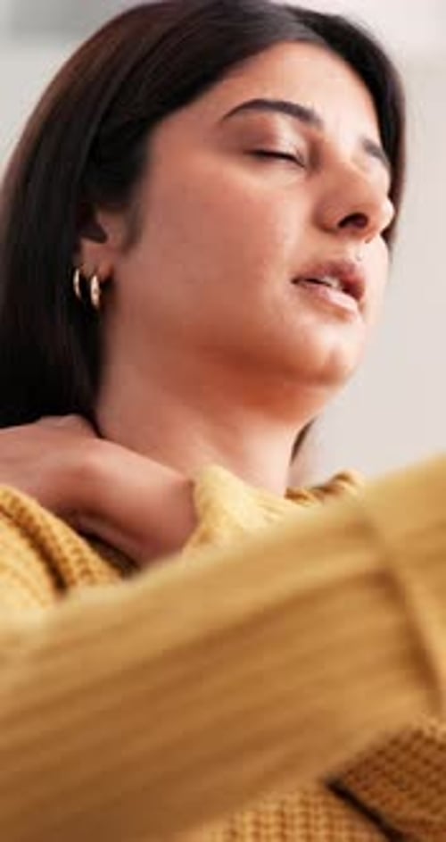 Woman Massaging Sore Neck in Yellow Sweater