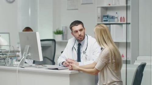 In Doctor's Office Young Woman Patient Talks to Her Male Doctor.