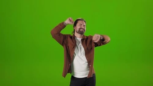 Positive Man Dancing Happily Over Green Studio Background