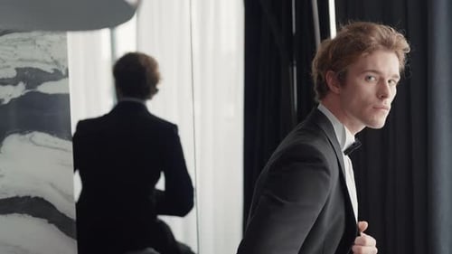Elegant Man in Tuxedo Adjusting Jacket Before Mirror