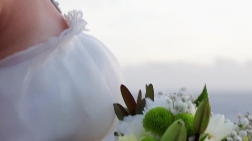 Bride Holds Flower Bouquet on Beach on Wedding Day