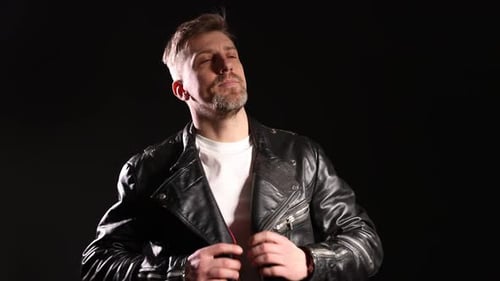 Brutal man in leather jacket on black background