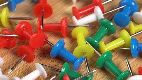 Colorful push pins rotating on the desk. Drawing pins for marking on the map of the Earth or city