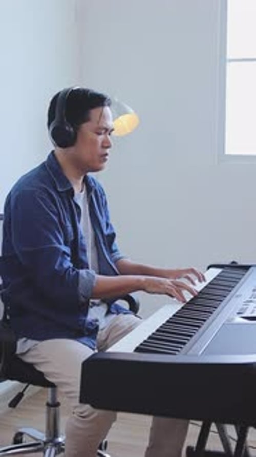 Asian Man Playing Keyboard In Studio