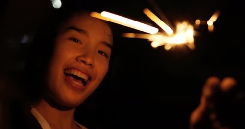 Asian pretty girl holding burning sparkler at night in New year