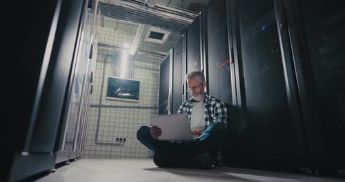 Mann sitzt auf dem Boden im Serverraum